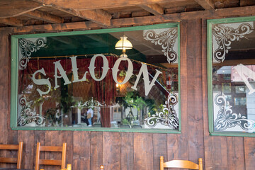 Western town saloon sign text on old windows and wooden farwest facade style entrance