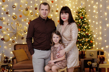 Beautiful family in christmas decorated room in gold colours