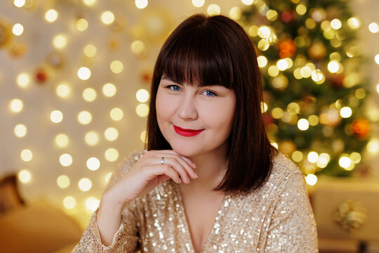 Portrait of beautiful woman in golden dress near christmas tree