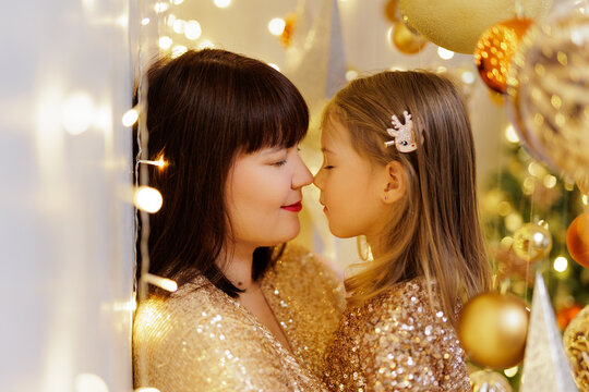 Mother and daughter posing nose to nose in christmas decorations