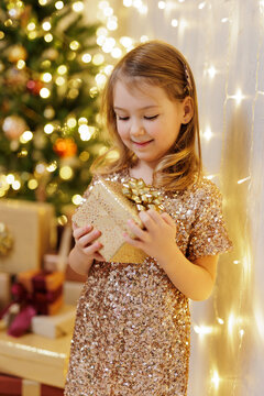 Little girl looking on gift near christmas tree