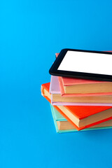 Modern e-book on stack of hardcover books on blue background