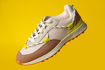 Beige sport running shoes on yellow studio background
