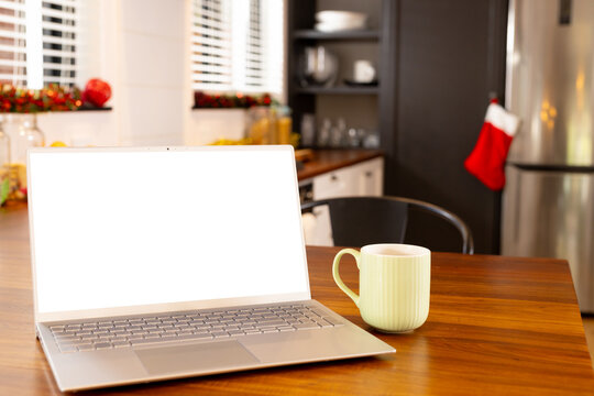 Laptop with copy space with mug lying on table top in kitchen