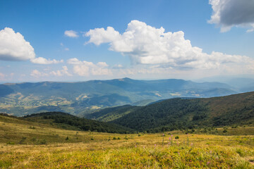 Beautiful view of the Ukrainian Carpathians to the mountains and valleys. Rocky peaks and wood of the Carpathians in late summer. Yellow and green grass, and the top of the mountain and the path to it