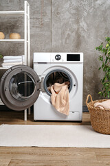 Fototapeta na wymiar Laundry room interior with washing machine near gray grunge wall