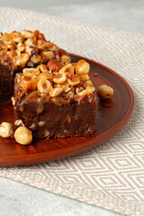 Brownie cake with nuts topping on plate close up