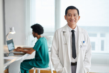 Portrait of smiling general practitioner in labcoat standing in medical office