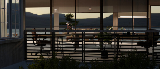 A modern office with no people at night seen through the glass wall from outside of a building.