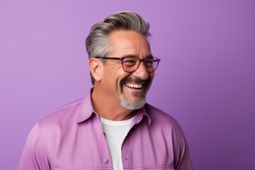 Portrait of happy senior man in eyeglasses laughing and looking at camera while standing against purple background - obrazy, fototapety, plakaty