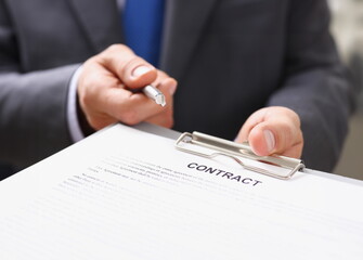 Male arm in suit offer contract form on clipboard pad and silver pen to sign closeup. Strike a...