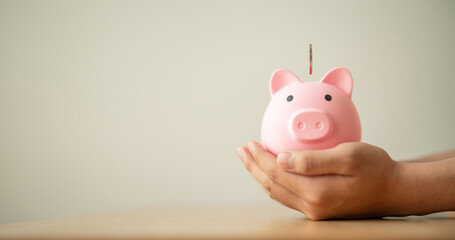 coins into piggy bank on hands for saving money, investment, success ,commission,  wealth and finance concept.