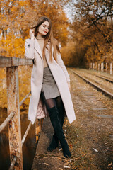 beautiful long-haired woman walks through the autumn streets. Railway, autumn, woman in a coat.
