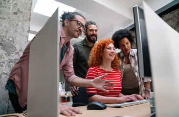 Diverse group of professionals meeting in office. IT programmers use computer, talk strategy