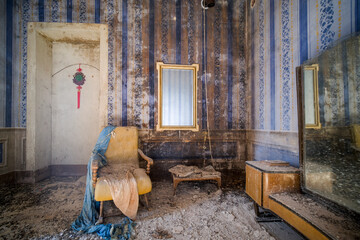 armchair and mirror in a striped room in an abandoned house