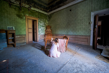girl kneeling near an abandoned baby cot
