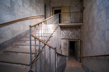 corridor with stone wall and wooden railing in an abandoned house