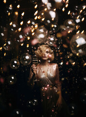 A luxurious cocktail party with champagne on  New Year's Eve. A young, elegant woman in a glittering gold dress toasts the holidays.