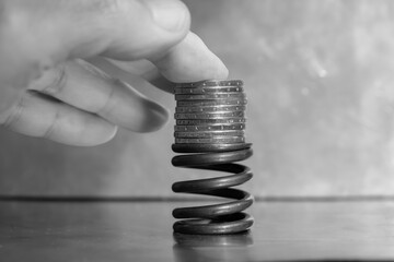 Coins on top of the metal spring. Human hand.