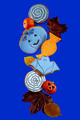 Painted Halloween gingerbread and autumn leaves on a blue background.