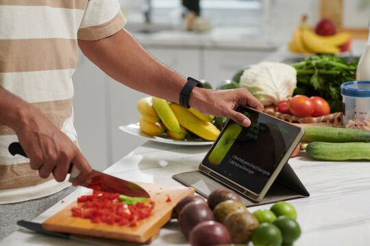 Cropped image of man opening recipe on digital tablet when cooking dinner at home