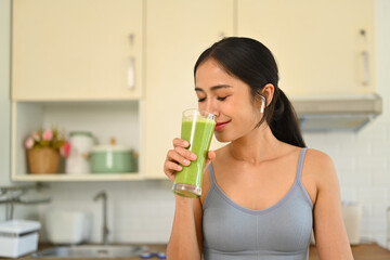 Charming young woman in sportswear drinking healthy vegetarian smoothie after morning workout. Healthy lifestyle concept