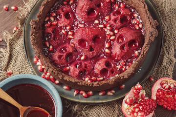 Halloween food. Homemade pie with jam and scary skull-shaped pears. Wooden rustic background and...