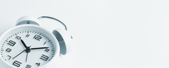 Close-up of a white alarm clock on a white background, ten o'clock. Blank space for text