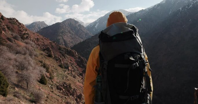 Epic camera follow shot of man with backpack climbing up trail on mountain pass. Genuine outdoor lifestyle. Autumn vacation. Overcoming obstacles travel difficulties, perseverance, will, courage