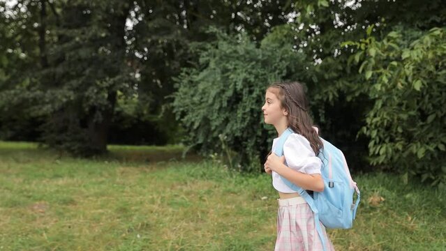 A little girl with a blue backpack on her shoulders goes to school. Learning at school.