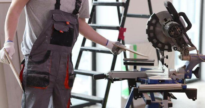Craftsman cuts laminate flooring on saw in carpentry workshop. Circular saw for wood machine
