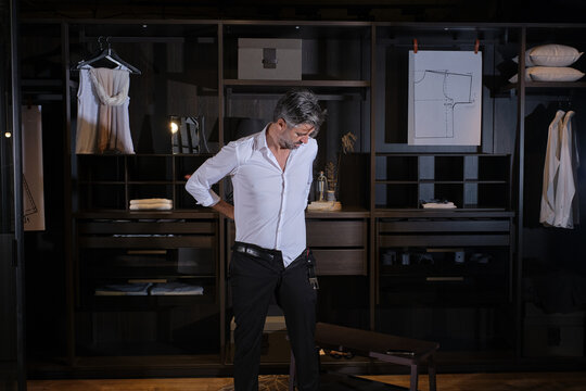 Mature man dressing in trousers at home