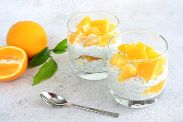 chia pudding dessert decorated with orange in drinking glasses with teaspoon