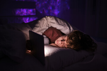 Fototapeta na wymiar Boy sleeping near tablet in bed at night