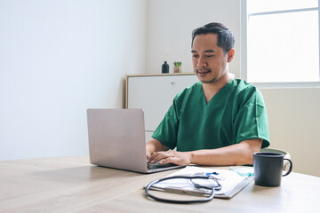 Young Asian doctor man using laptop working at hospital