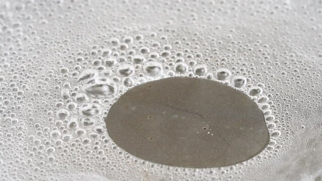 Water boiling and evaporating steam from a Teflon Pan - macro