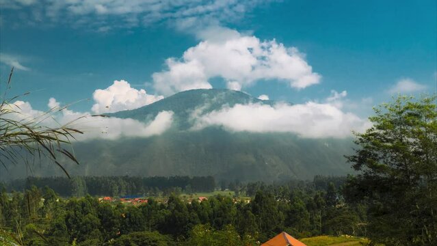 Daytime timelapse footage in Oxapampa, Peru. It features a mountain covered in forests with fast-moving clouds above. The blue sky and forested lands are prominent.