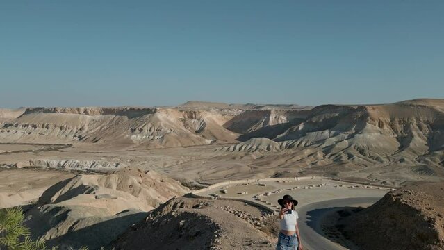 European woman wearing casual clothes taking selfie, the Negev Desert in Israel is visible in the background over mountains, sandy hills and rock formations.
Near David and Paula Ben Gurion gravesite.