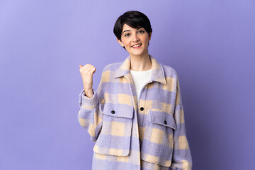 Woman with short hair isolated on purple background pointing to the side to present a product