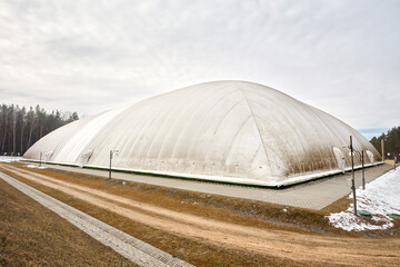 Inflatable air dome stadium. Inflated Football soccer air dome. Modern architecture example pneumatic stadium dome with heat generators, hot air blower and air conditioning system near winter forest. © R_Yosha