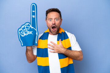 Middle age caucasian sports fan man isolated on blue background surprised and shocked while looking...