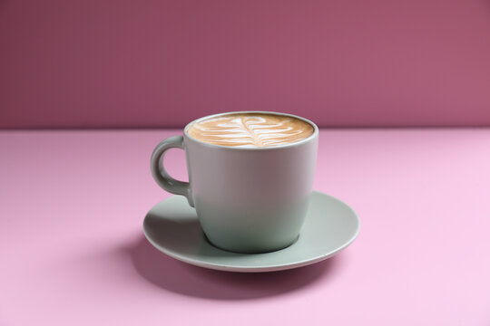hot cappuccino with latte art isolated in pink background
