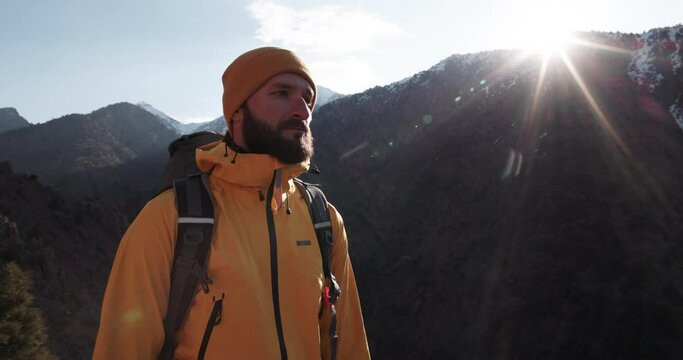Male adventurer at top of hill. Outumn day on rocky mountain with autumn greenery, man indulges his wanderlust, exploring peaceful mountain scenery. Captivated by nature's splendor. Cinematic 