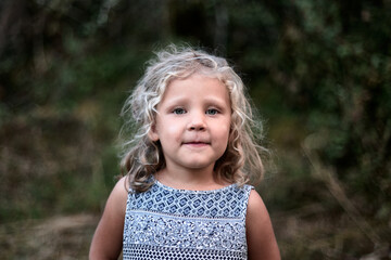 portrait petite fille charmante bouclé au yeux bleu dans la nature