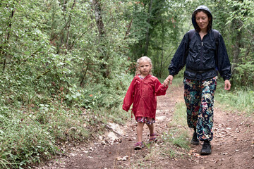 promenade sous la pluie, petite fille en rouge tenant la main de sa maman dans la forêt - obrazy, fototapety, plakaty