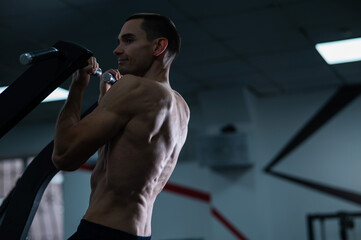 Back view of shirtless man with pull-ups in gym. Narrow grip.