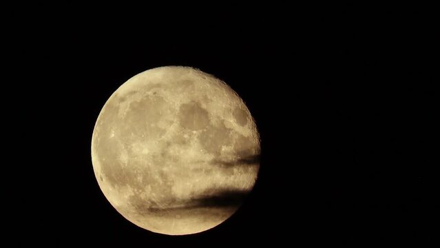 Full Moon is covered by flying natural black clouds, like in thrillers and horror films, in the style of Halloween. Cloudy dark night sky. Real shooting