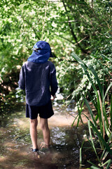 Exploration enfantine d'un enfant, un garçon marchant dans un ruisseau, entourés de verdure