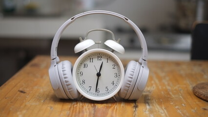 Alarm clock with headphones on wooden background. Space for your text