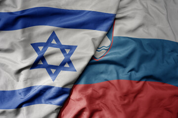 big waving national colorful flag of israel and national flag of slovenia .